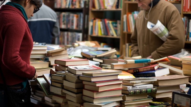 Люди выбирают бумажные карты и книги в магазине.