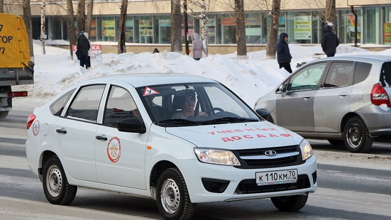 Российские автошколы перешли на новые программы с увеличенной практикой и правилами для электросамокатов Учебный автомобиль Lada Granta с маркировкой автошколы на улице