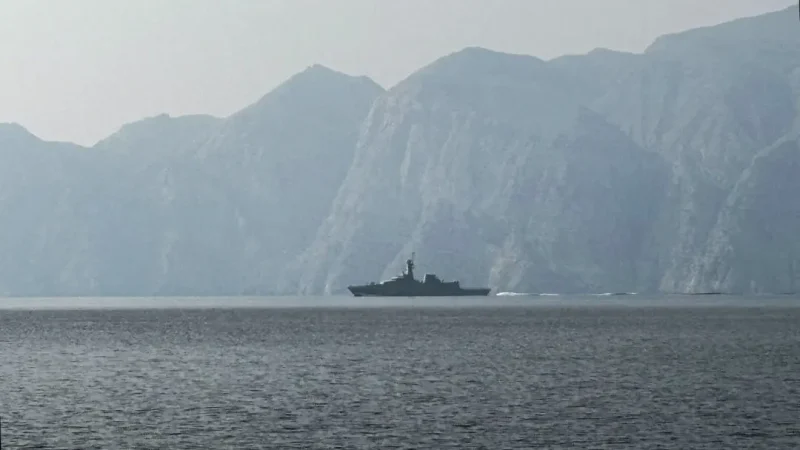 Силуэт военного корабля в тумане на фоне скалистых берегов Ормузского пролива в Иране во время начала военного конфликта 2026 года.