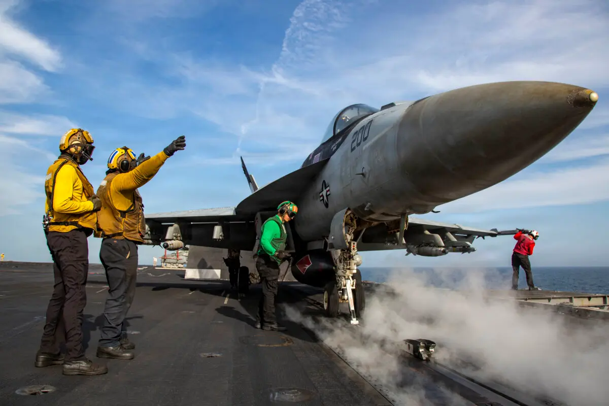 Американский моряк подаёт сигнал истребителю F/A-18E Super Hornet, готовому к взлету с палубы авианосца «Авраам Линкольн» типа «Нимиц» в Аравийском море, 15 апреля 2026 года.
