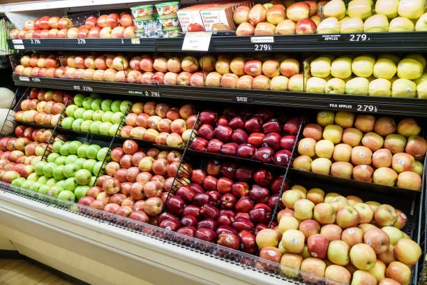 Прилавок с рядами яблок разных сортов в продуктовом магазине