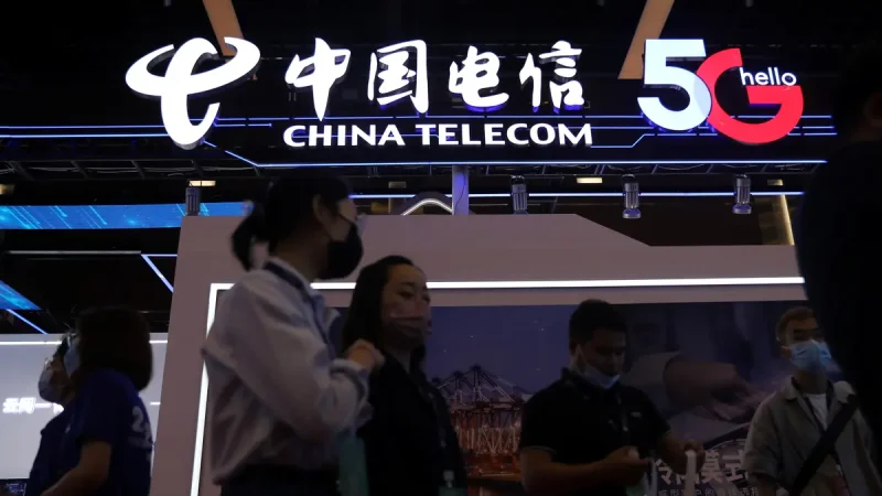 Светящаяся вывеска China Telecom 5G и люди в масках на переднем плане.