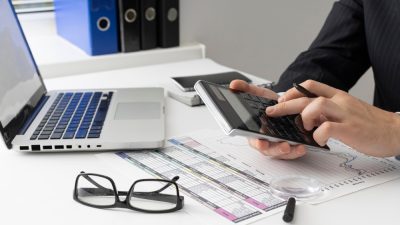 Бухгалтер производит расчет НДС на калькуляторе в офисе