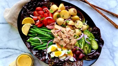Классический салат нисуаз с тунцом, овощами и яйцом на черном блюде